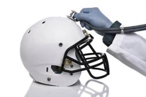 Football helmet with physician holding a stethoscope.