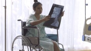 An injured woman in a wheelchair checking her x-ray result.
