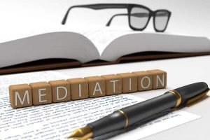 an open book laid out with glasses, a paper, a pen, and the word mediation