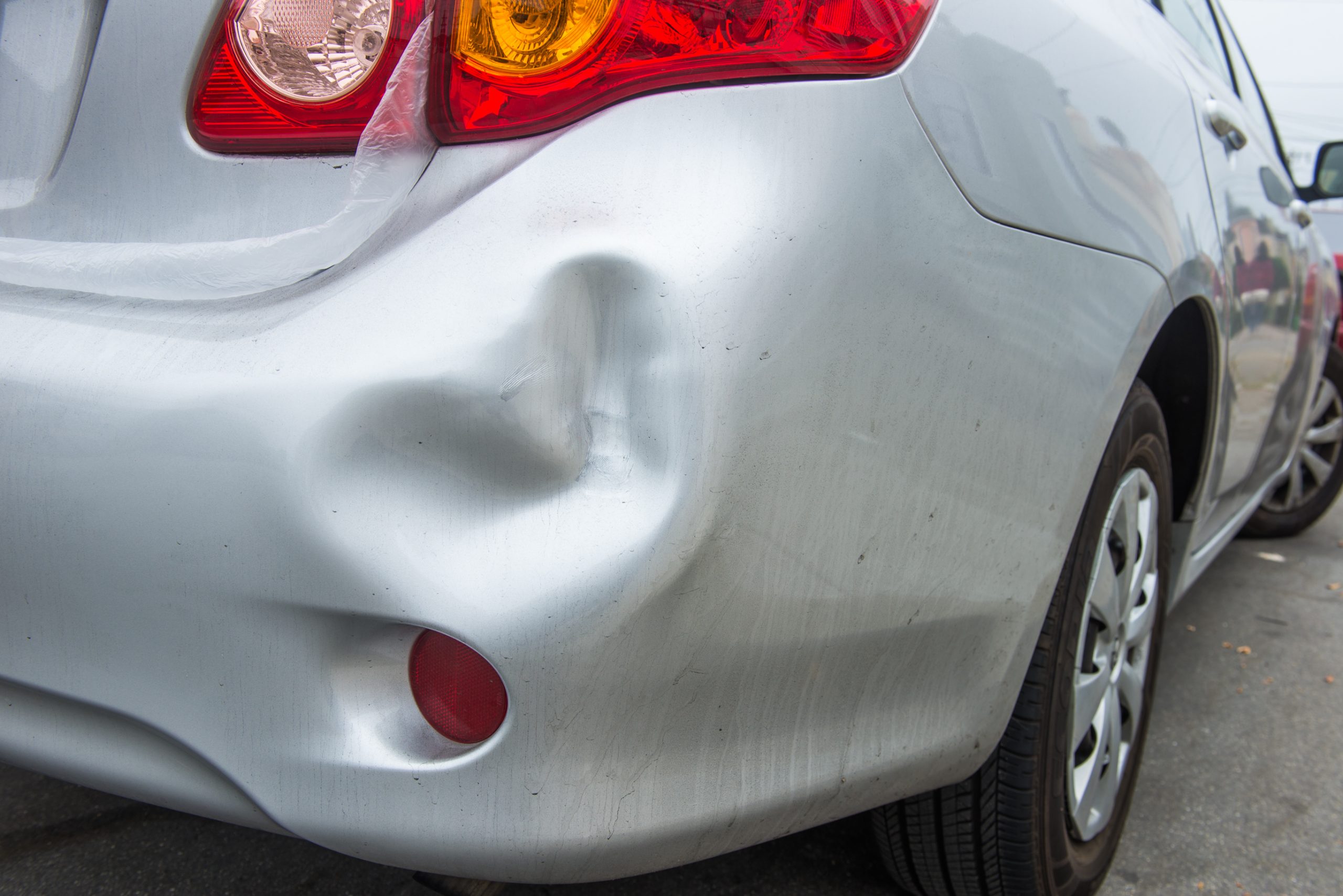 A car has a dented rear bumper